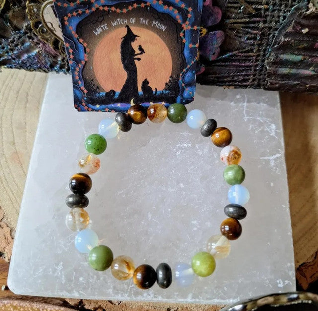 Multicolor crystal bead bracelet with round green, gold, black, and clear opal beads on a card